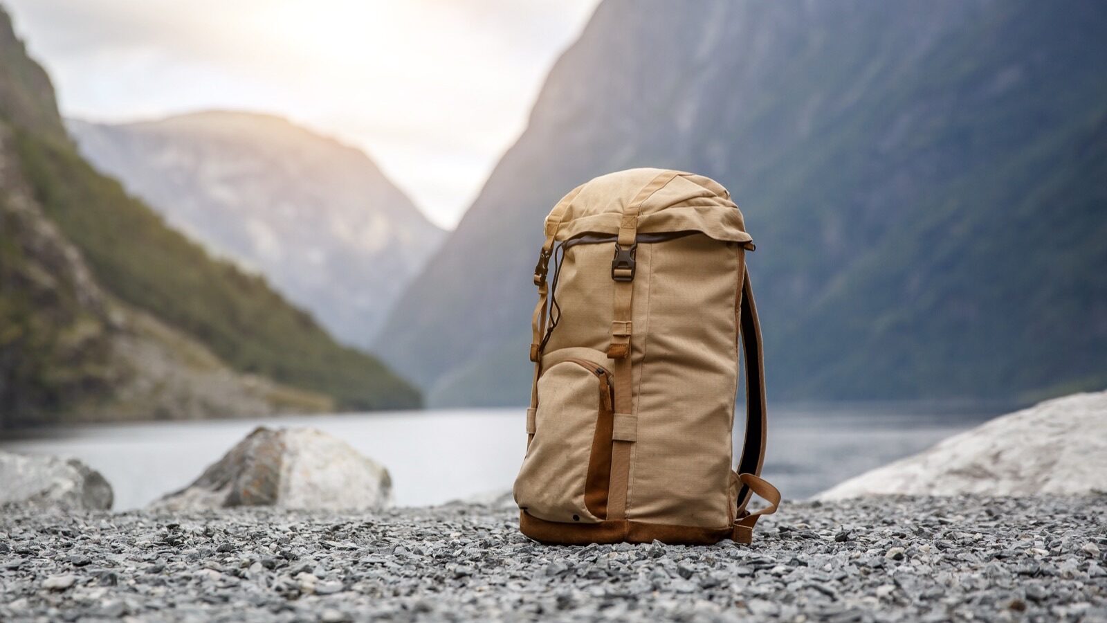 Sac à dos de randonnée posé sur des galets face à un fjord