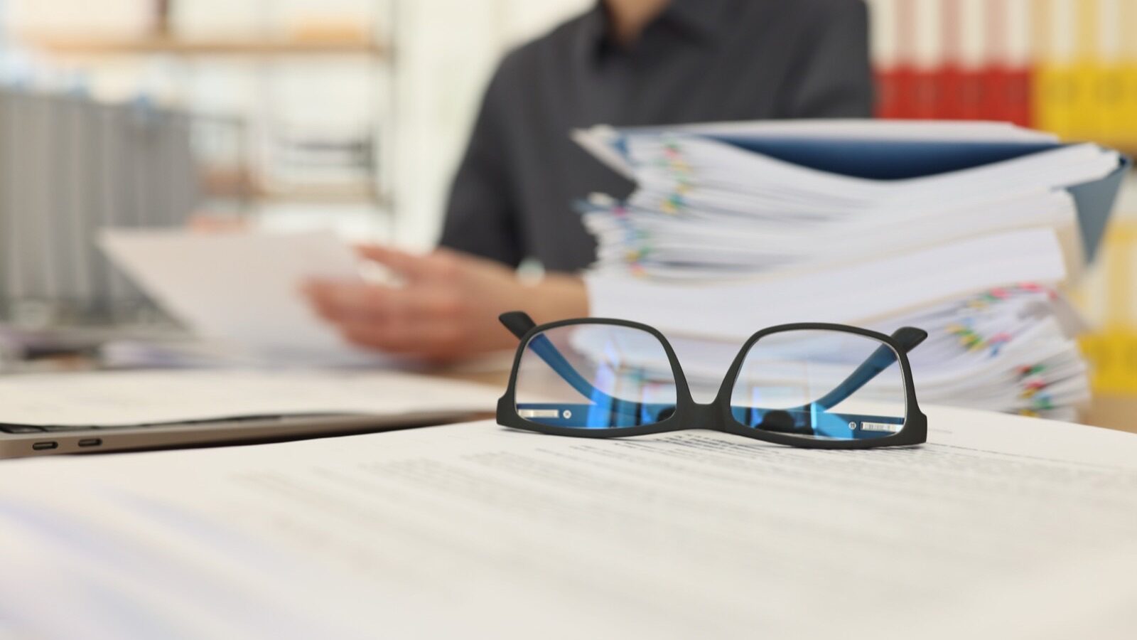 Paire de lunettes posée sur une pile de documents et de dossiers de bureau