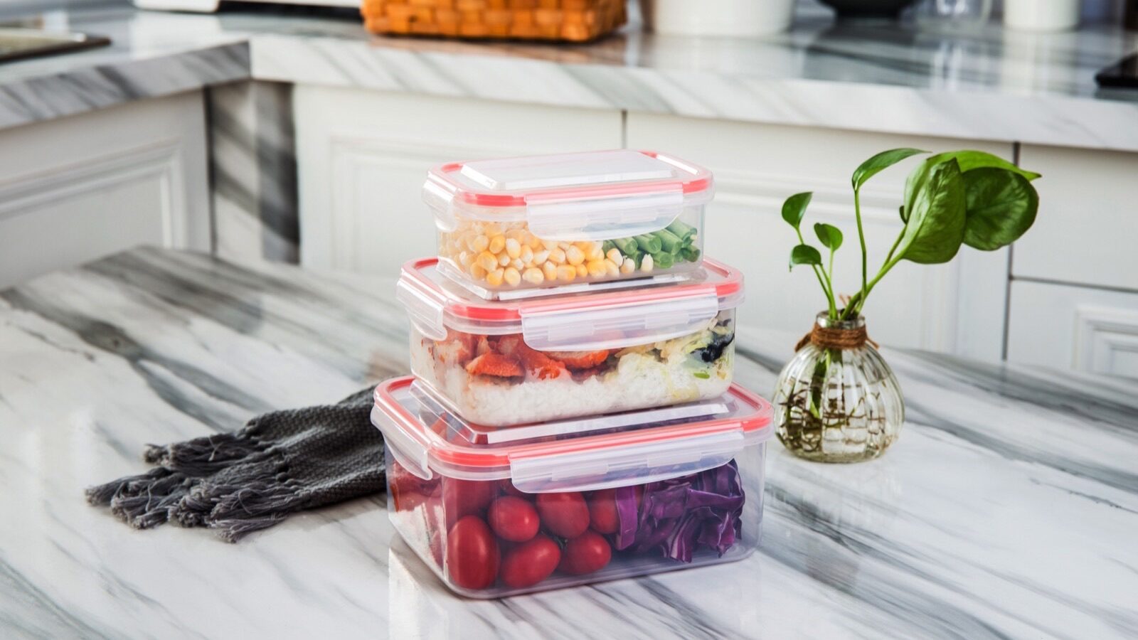 Trois boîtes de conservation alimentaire en plastique empilées sur un plan de travail